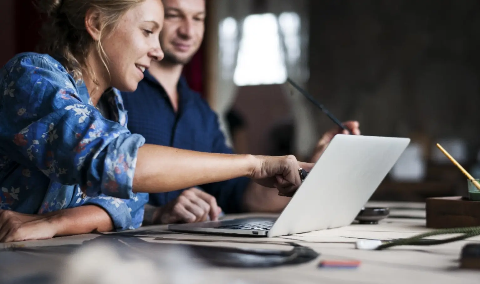 Two colleagues reviewing work together on a laptop